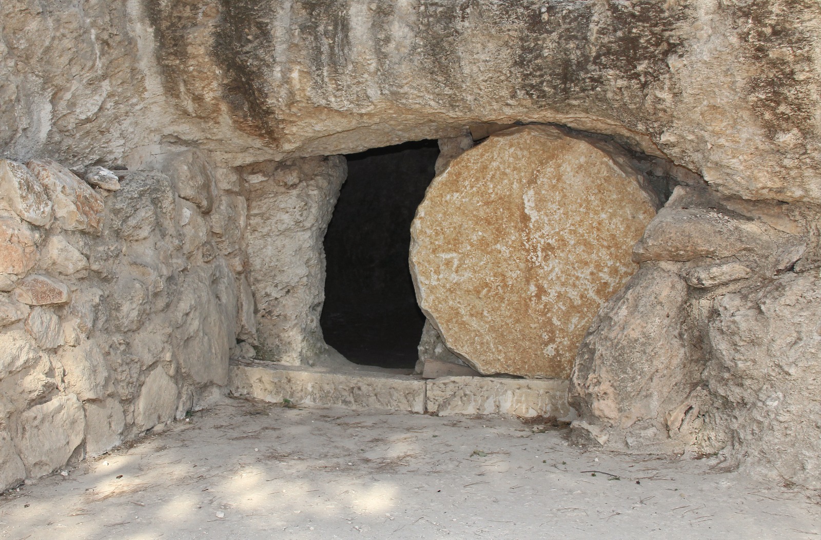  An open rock-cut tomb with a large stone rolled in front of the entrance believed to be the burial place of Jesus Christ.