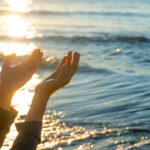 woman hands praying for blessing from god during sunrise background. Hope concept.