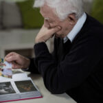 Widower looking at the photos and remembering deceased wife