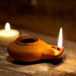 Ancient Middle Eastern oil lamp made in clay on wood table with candle. Deepavali Oil Lamp / Oil Lamp / Festive Oil Lamp / Burning the midnight oil