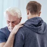 With you. Upset senior man closing eyes and hugging man