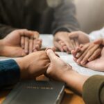 Group of young Christians praying, holding hands and praying together The concept of praying to God in the home as a team Pray to God with the Bible for forgiveness and faith.